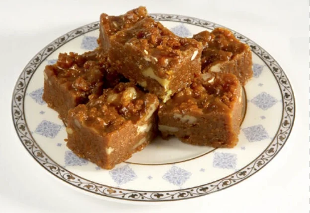 Habshi Halwa topped with almonds and pistachios on a serving tray