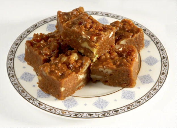 Habshi Halwa topped with almonds and pistachios on a serving tray
